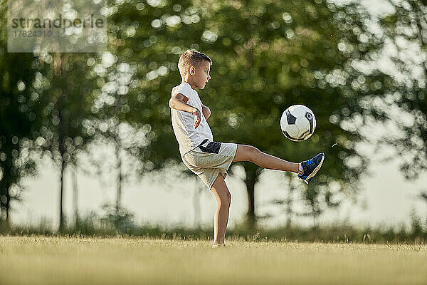 Junge spielt an einem sonnigen Tag Fußball