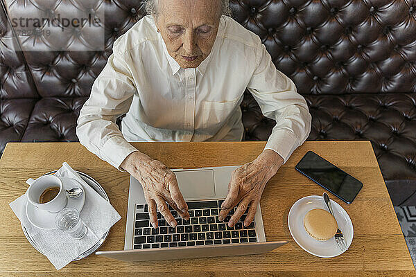 Ältere Frau arbeitet am Laptop im Café