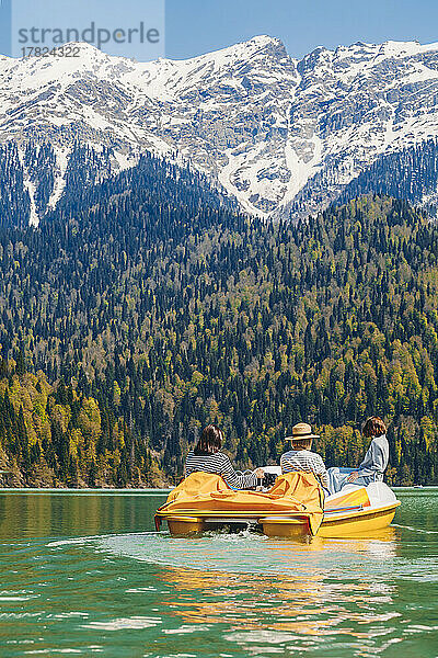 Freunde fahren an einem sonnigen Tag mit dem Tretboot am Ritsa-See