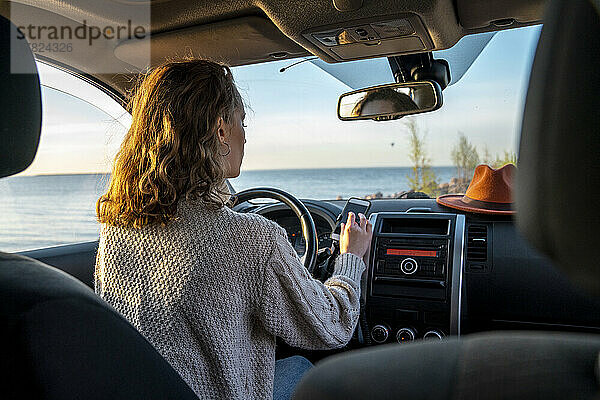 Junge Frau benutzt Smartphone im Auto