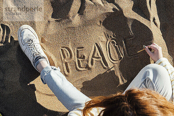Frau schreibt Frieden auf Sand am Strand