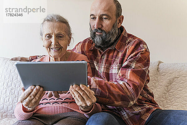 Mann bringt Seniorin zu Hause Tablet-PC bei