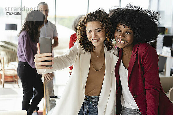 Geschäftsfrauen machen im Büro ein Selfie mit dem Smartphone