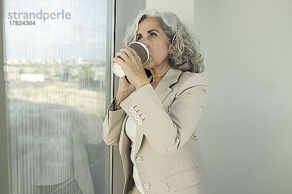 Geschäftsfrau trinkt Kaffee aus Einwegbecher im Büro