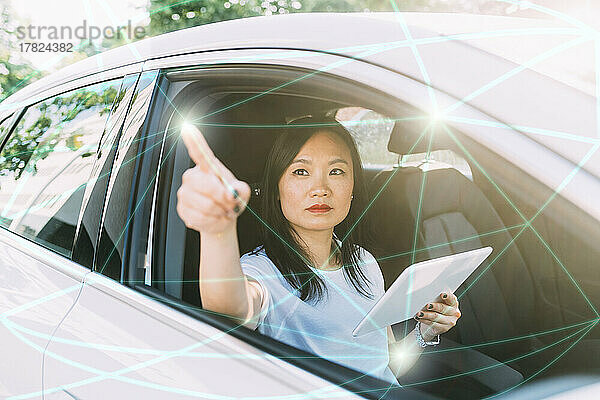 Geschäftsfrau mit Tablet-PC verbindet Linien und Punkte auf virtuellem Bildschirm im Auto