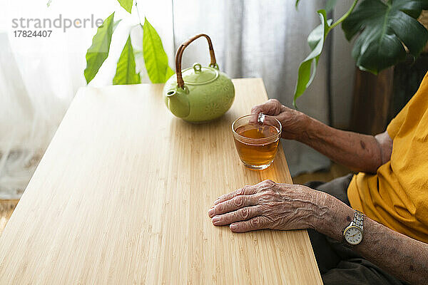 Ältere Frau mit Teetasse sitzt am Tisch
