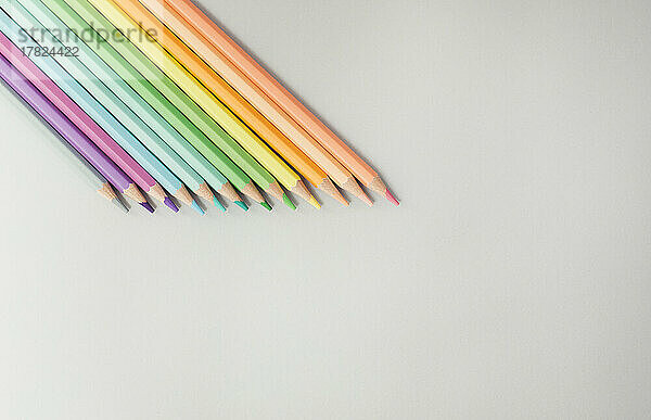 Studio shot of row of colored pencils lying against white background