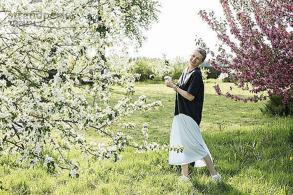 Glückliche Frau mit weißen Blumen im Garten