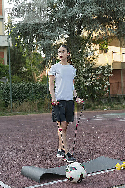 Junge Frau trainiert mit Widerstandsband auf dem Fußballplatz