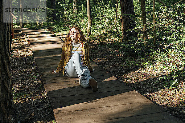Frau sitzt auf Fußweg im Wald