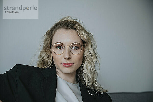 Selbstbewusste Geschäftsfrau mit blonden Haaren und Brille