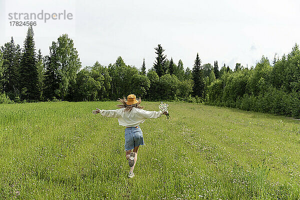 Frau mit Kamillenblüten läuft auf Gras