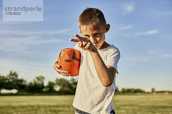 Boy with rugby ball gesturing on sunny day