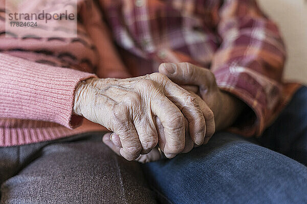 Reifer Mann hält die Hände einer älteren Frau zu Hause