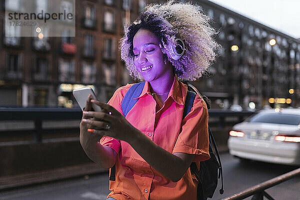 Frau benutzt nachts Smartphone in der Nähe von Geländer
