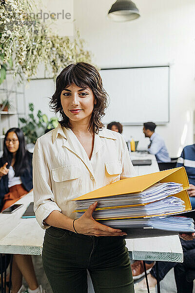 Selbstbewusste Geschäftsfrau hält Akten im Coworking-Büro