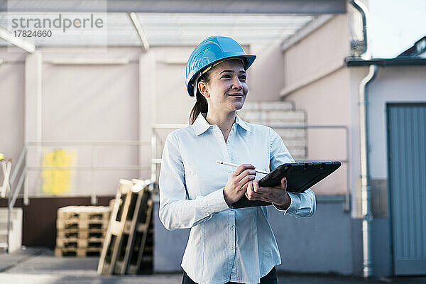 Lächelnde Architektin mit Tablet-PC in der Fabrik