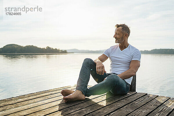 Smiling mature man sitting on jetty