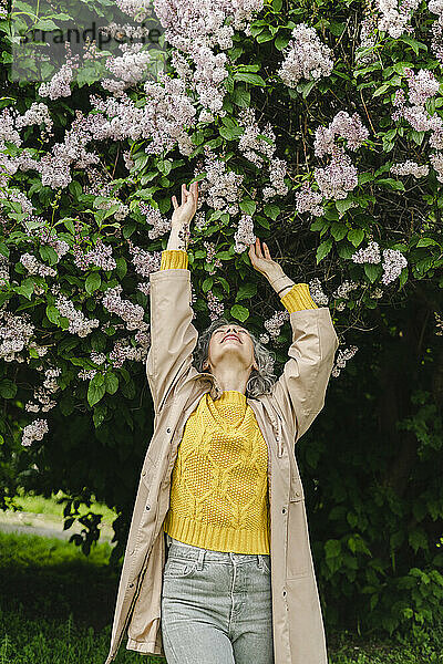 Frau berührt Blumen  die unter Blumen im Park stehen