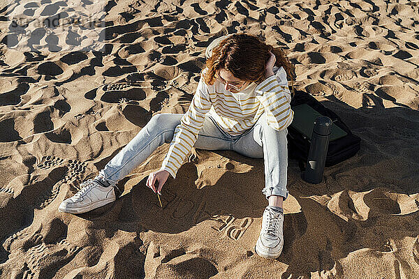 Junge Frau schreibt auf Sand am Strand