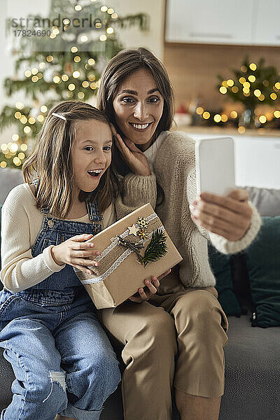 Fröhliche Mutter macht zu Hause ein Selfie mit ihrer Tochter per Handy