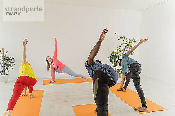 Men and women doing Utthita Parsvakonasana exercise at yoga studio