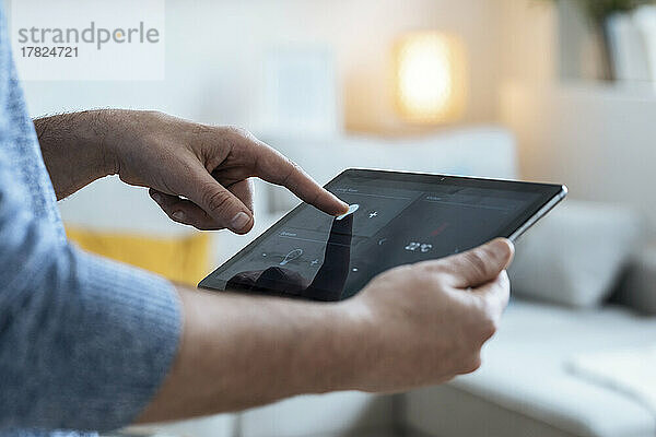 Hände eines reifen Mannes  der einen Tablet-PC im Smart Home nutzt