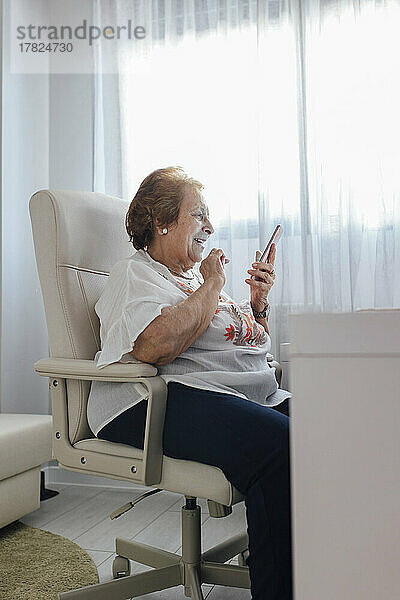 Glückliche ältere Frau  die zu Hause ihr Mobiltelefon benutzt