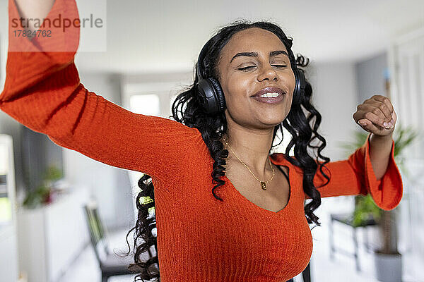 Glückliche Frau tanzt zu Hause mit Kopfhörern