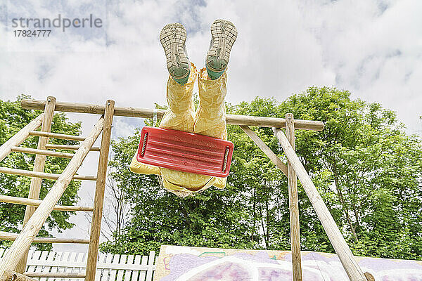 Mädchen schwingt auf Schaukel auf Spielplatz