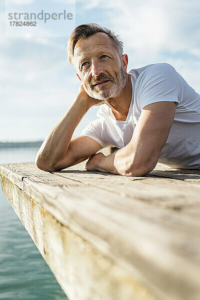 Reifer Mann liegt und blickt vom Pier aus auf die Aussicht