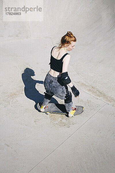Teenager skatet an sonnigem Tag im Skateboardpark
