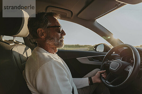 Reifer Mann mit Sonnenbrille fährt Auto