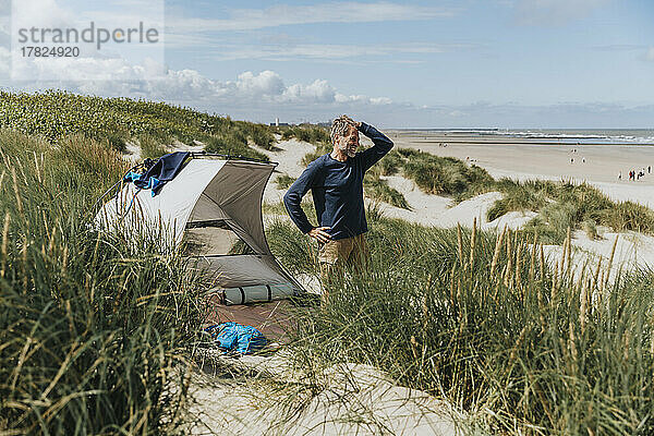 Glücklicher Mann  der an einem sonnigen Tag am Strand campt