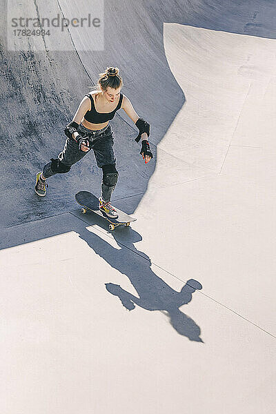 Teenage girl skateboarding at skateboard park