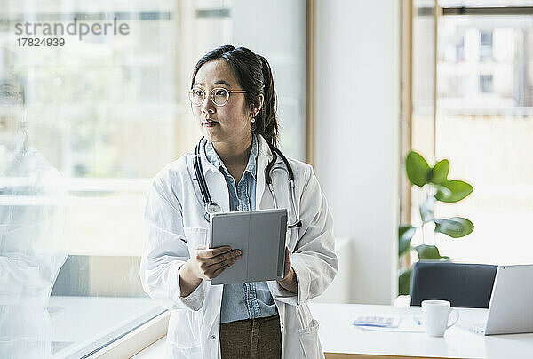 Ärztin mit Tablet-PC steht im Büro