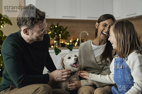 Glückliche Familie mit Hund  die gemeinsam die Weihnachtszeit zu Hause genießt