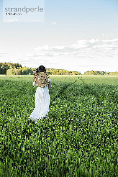 Frau mit Hut steht auf dem Feld