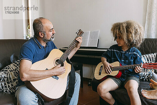 Mann bringt seinem Sohn zu Hause das Gitarrespielen bei