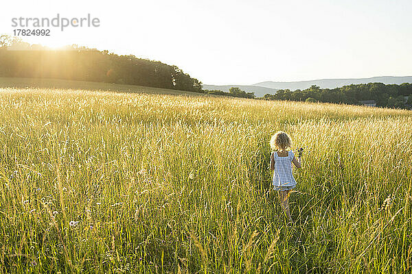 Mädchen läuft an einem sonnigen Tag auf dem Feld
