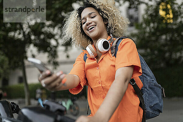 Lächelnde Frau mietet Elektrofahrrad über mobile App