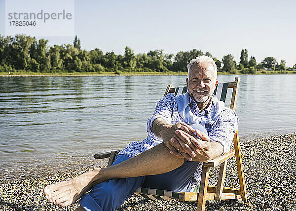 Lächelnder älterer Mann am Flussufer an einem sonnigen Tag