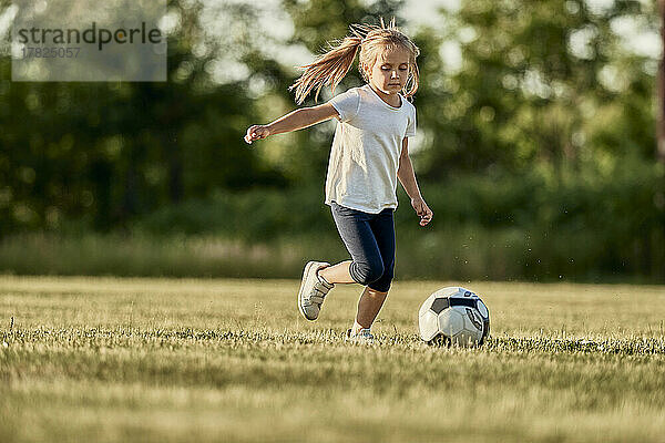 Blond girl playing soccer on sunny day