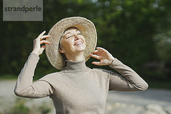 Glückliche reife Frau mit geschlossenen Augen genießt den sonnigen Tag