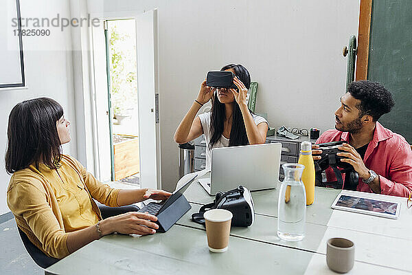 Geschäftsfrau trägt VR-Brille von gemischtrassigen Kollegen im Büro