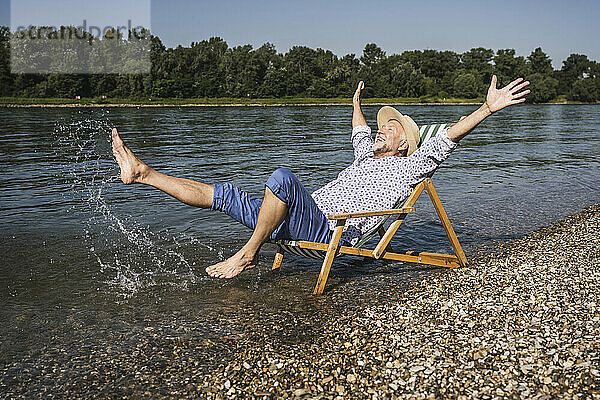 Glücklicher Mann  der an einem sonnigen Tag am Flussufer genießt