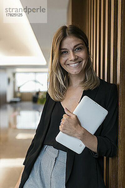 Lächelnde Geschäftsfrau hält Tablet-PC in der Hotellobby