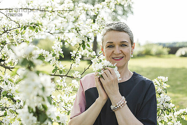 Lächelnde Frau mit weißer Blume im Garten