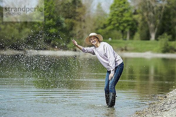 Glückliche reife Frau  die Wasser spritzt und am See genießt