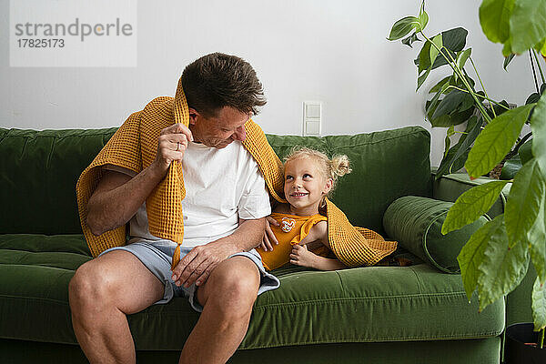 Vater und Tochter spielen zu Hause mit Decke